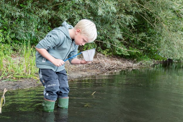 Ein Junge steht mit einem Kescher im Wasser Ein Junge steht mit einem Kescher im Wasser