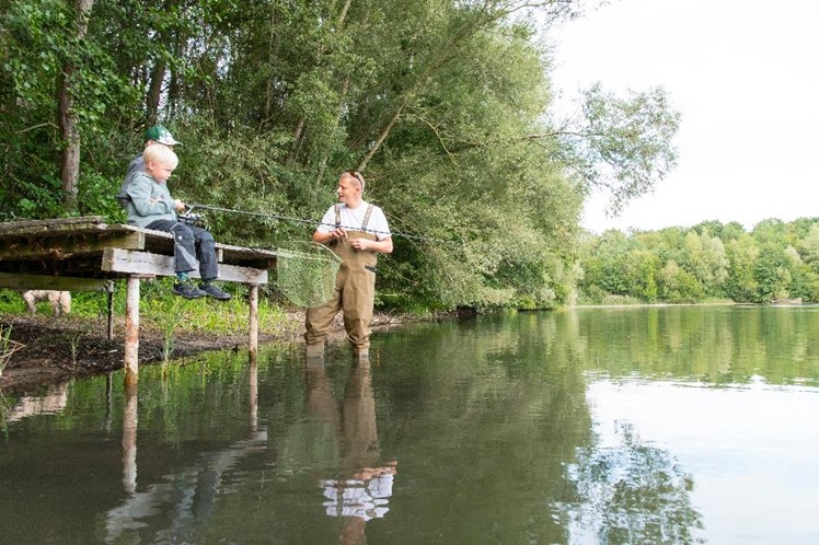 Angeln Zwei Kinder und ein erwachsener Angler an einem Steg