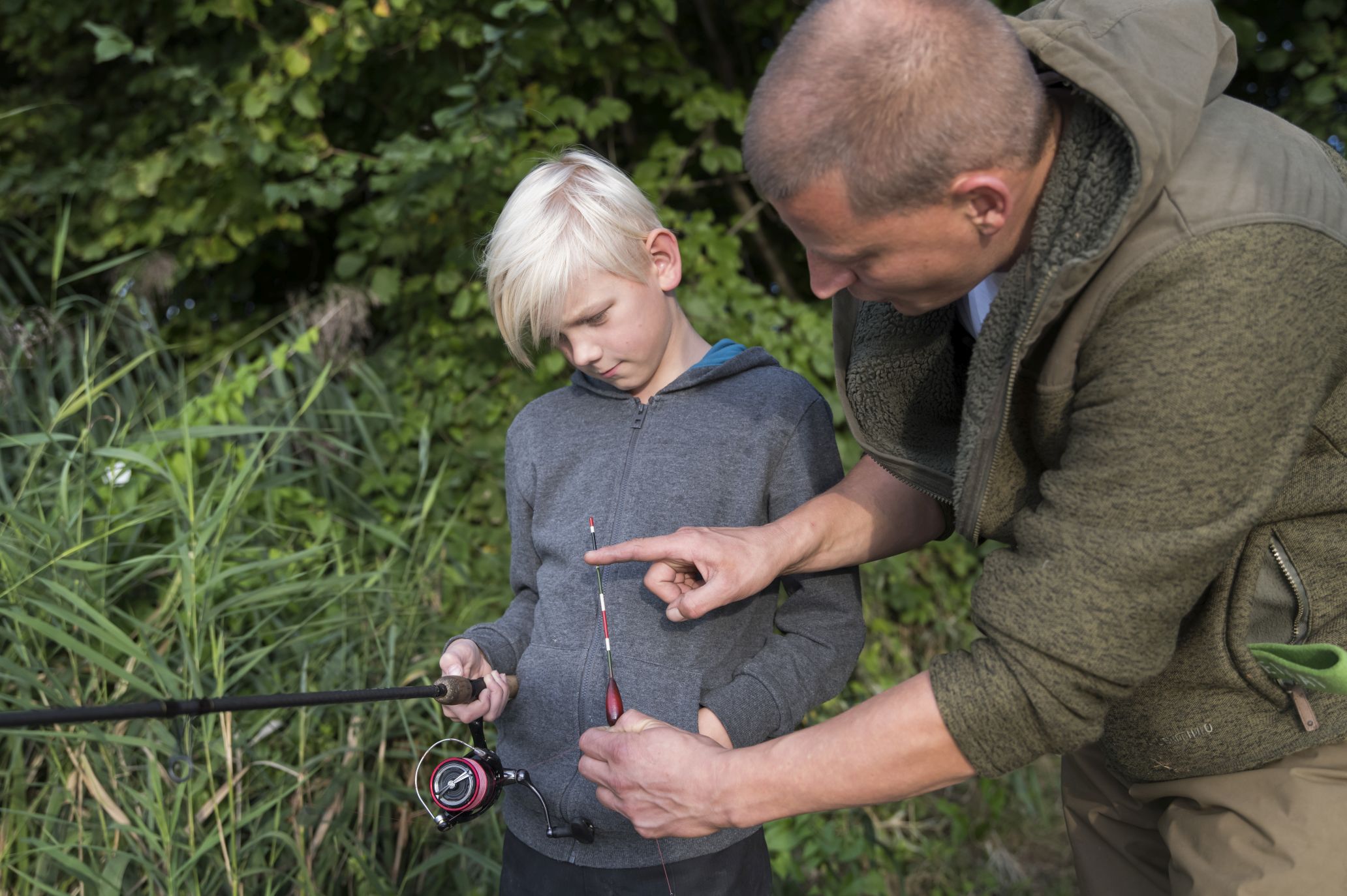Ein Junge angelt gemeinsam mit einem Erwachsenen